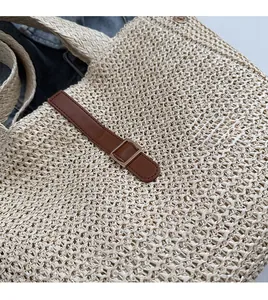 Gros plan d'un sac cabas en paille tressée avec détail de sangle en cuir et boucle