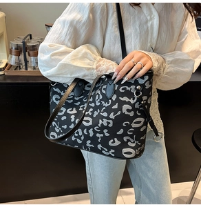 Dettaglio di una borsa tote leopardata con manici in pelle nera su un outfit casual