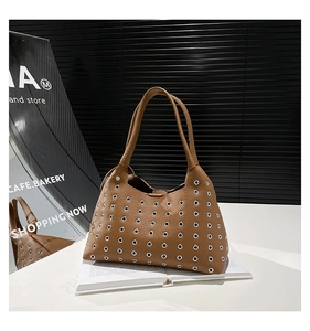 Detailed close-up of brown leather hobo bag with silver grommets and rivet hollow-out design