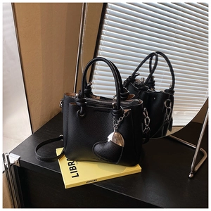 Detail of black lychee grain leather bucket bag with heart charm and mirror reflection