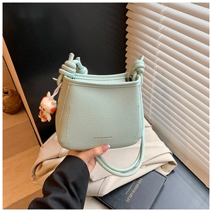 Detail of mint green bucket bag with lychee grain texture and cute rabbit charm