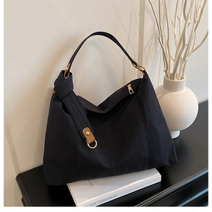 Detail of black large capacity tote bag with golden metal rings and brown leather buckle