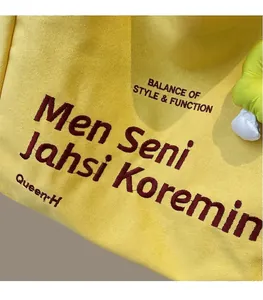 Close-up of bright yellow canvas tote bag with high-quality embroidery and rough texture