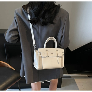 Detail of white leather and canvas crossbody bag worn by model showing side profile and straps
