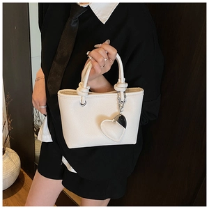 Detail of cream white leather bucket bag with litchi texture and heart pendant