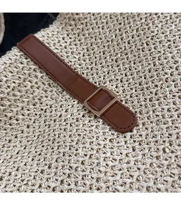 Détail de la texture en paille tressée avec sangle en cuir brun et boucle dorée
