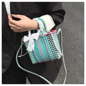 Detail of colorful woven handbag with white lace bow and gray shoulder strap for women