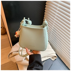 Close-up of light green bucket bag with lychee texture and knot handle detail