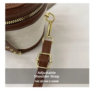 Detail of adjustable leather strap with gold hardware and floral pattern bucket bag