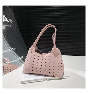 Detailed close-up of pink lychee leather handbag with metallic eyelet rivet decorations