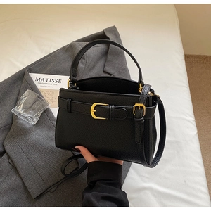Détail du sac à main noir grainé avec fermoir doré et bandoulière en cuir élégante