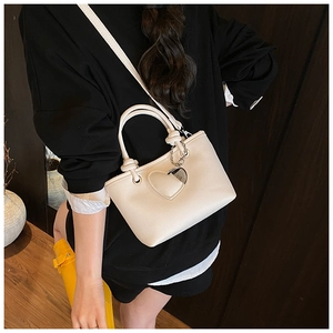 Detailed texture of a white lychee leather bucket bag with a heart-shaped charm accessory