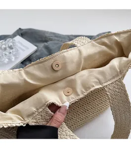 Détail du sac cabas en paille beige montrant la doublure et le fermoir magnétique