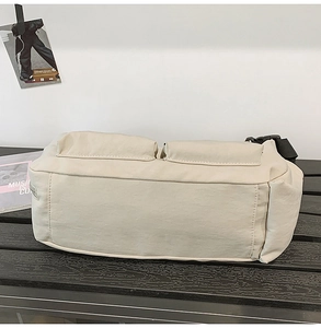 Detail of beige nylon messenger bag with two front pockets and black adjustable strap
