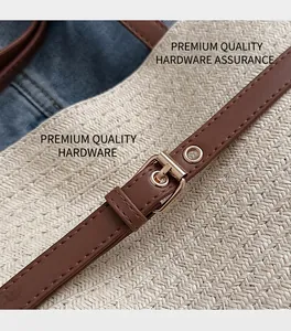 Detail of brown leather strap with gold buckle on a beige woven straw beach tote bag