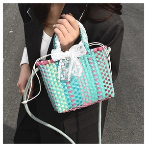 Detail of colorful woven basket bag with white lace bow and adjustable shoulder strap