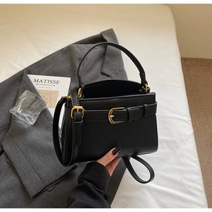 Détail du petit sac carré en cuir noir grainé avec boucle dorée et bandoulière réglable