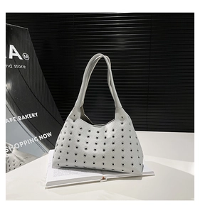 Detail of light-colored leather tote bag featuring modern metal eyelet embellishments