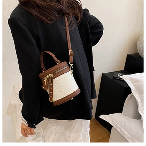 Detailed close-up of brown leather and beige quilted fabric bucket bag on a female model