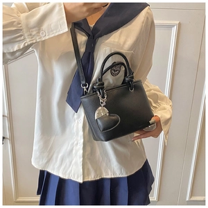 Detail of black lychee grain leather bucket bag with knot handle and heart charm detail