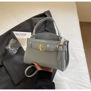 Détail d'un sac en cuir grainé bleu-gris avec boucle dorée et poignée élégante
