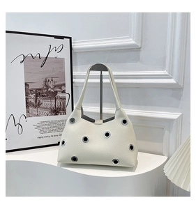 Detail of cream lychee leather underarm bag with decorative silver metal eyelets