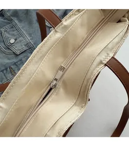 Detail of a woven tote bag with smooth silver zipper and beige fabric lining
