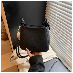 Close-up of black pebble texture bucket bag with knot strap and metallic logo
