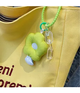 Detail of creative flower plush pendant with green acrylic chain on canvas tote bag
