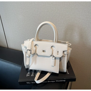 Detail of white lychee pattern leather handbag with silver hardware on art books