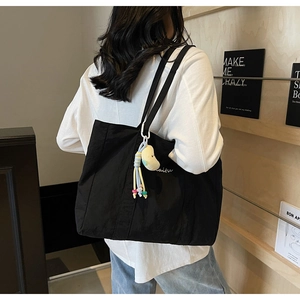 Large black canvas tote bag with shoulder straps and a cute yellow plush charm detail