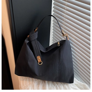 Macro view of charcoal grey tote bag with brown leather accents and gold zipper detail