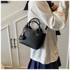 Detail of black lychee leather bucket bag with silver heart charm and crossbody strap