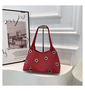 Detail of dark red lychee grain leather underarm bag with silver metal eyelet studs