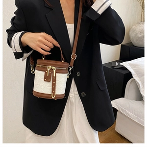 Detail of a two-tone mini bucket bag in white textured fabric and brown leather