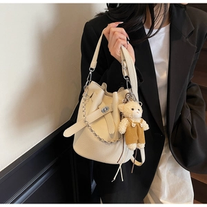 Detail view of cream bucket bag with litchi grain leather and cute bear charm