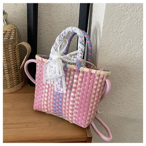 Detail of hand-woven crossbody bag with pink and blue stripes and a white lace bow