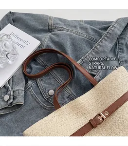 Detail of woven straw tote bag with brown leather shoulder straps on denim fabric