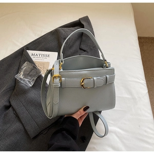 Détail du sac en cuir bleu clair avec motif litchi, boucle dorée et bandoulière fine