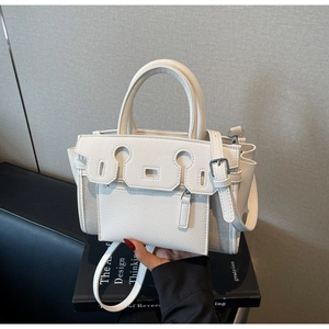 Detail view of white lychee leather texture and classic lock closure on handbag