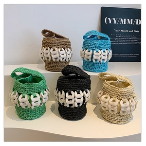 Detail shot of handwoven straw bucket bags in five colors on a minimalist display