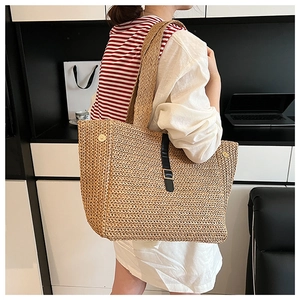 Détail du sac cabas en paille tissée avec bride en cuir noir et fermoir métallique