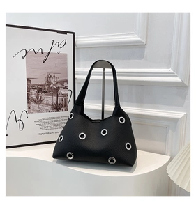Detailed macro view of black lychee grain leather handbag with six silver metal eyelets
