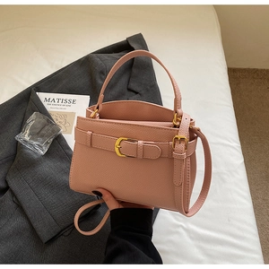 Détail du sac à main rose clair en cuir grainé avec finitions dorées et poignée fixe