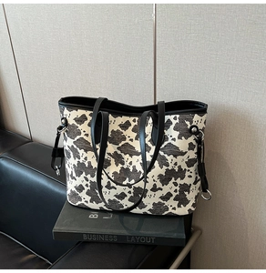 Dettaglio della borsa tote con stampa mucca, spalline in pelle nera e fibbia in metallo