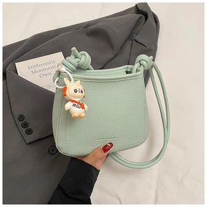 Detail of light green bucket bag with leather texture and cute astronaut charm