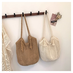 Close-up of hand-woven hollow tote bags with tassels in khaki and cream white colors