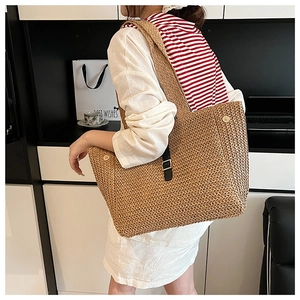Détail d'un grand sac cabas en paille avec lanières en cuir noir et boucle argentée