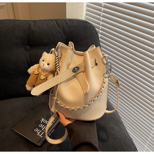 Detail of off-white lychee texture bucket bag with silver chain and bear charm