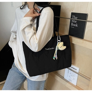 Detail of black canvas tote bag with white embroidery and moon beaded charm accessory